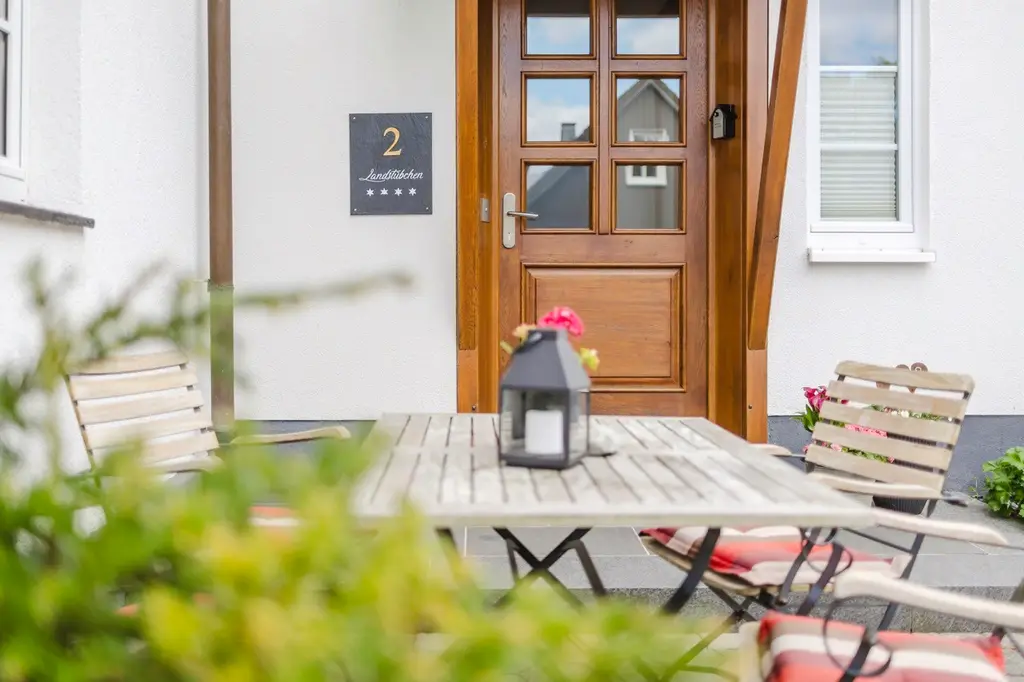 Eingang der Ferienwohnung mit Holztür und Gartentisch davor