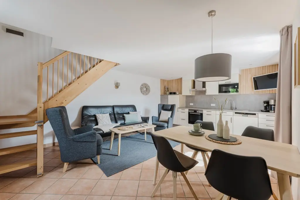 Wohnküche der Ferienwohnung mit Sofa, Esstisch und Treppe ins Obergeschoss