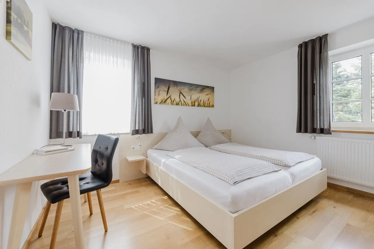 Lichte slaapkamer van het appartement met tweepersoonsbed en bureau