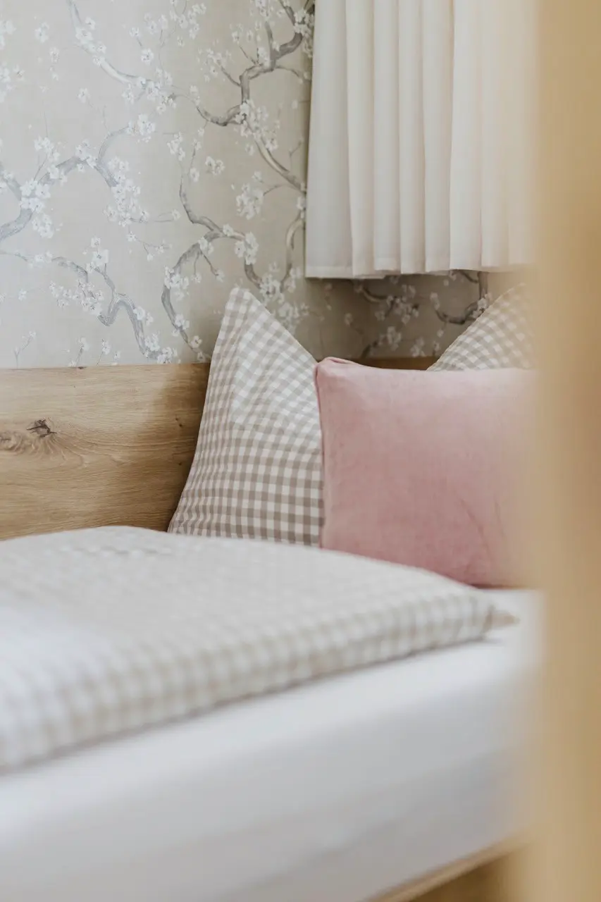 Frisch bezogenes Bett mit karierten und rosa Kissen – Bettwäsche ist inklusive