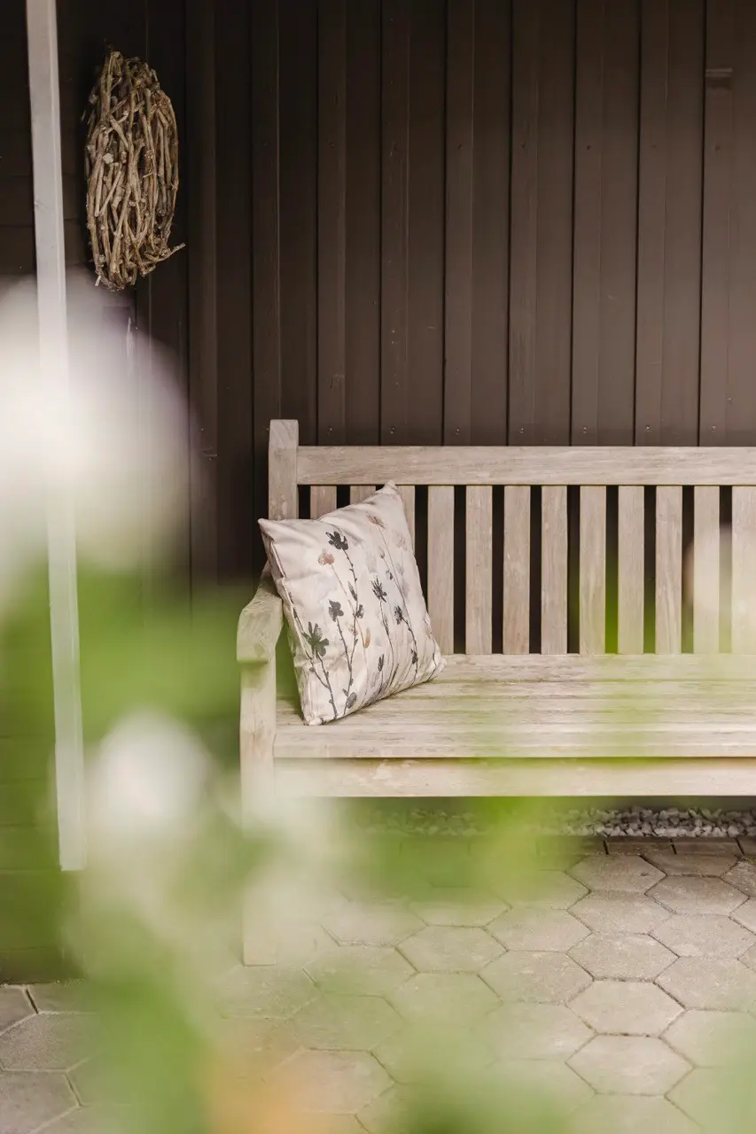 Holzbank auf der überdachten Veranda des Ferienhauses