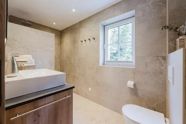 Badezimmer im Ferienhaus mit Waschtisch in Betonoptik und Fenster
