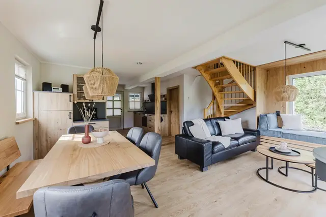 Großer Holz-Esstisch im Ferienhaus mit Blick auf Wohnbereich und Holztreppe