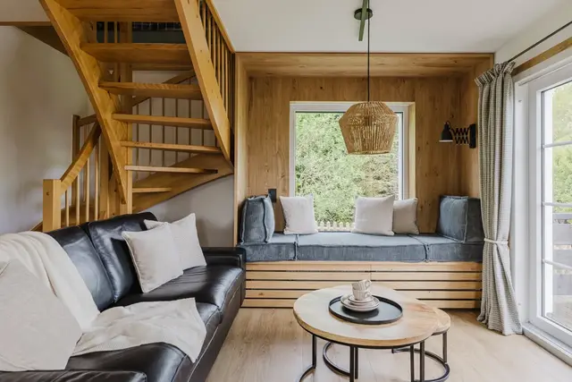 Sitzecke mit Ledersofa, Couchtisch und Fensterbank unter der Holztreppe im Ferienhaus