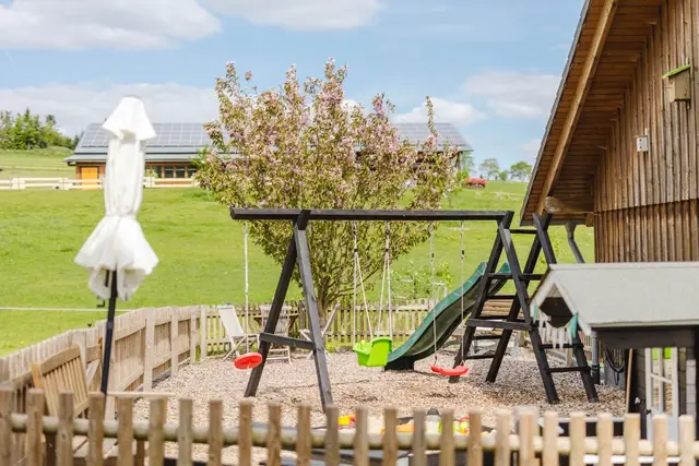 Spielplatz auf dem Hof mit Schaukel, Rutsche und Blick über die Wiesen des Sauerlands
