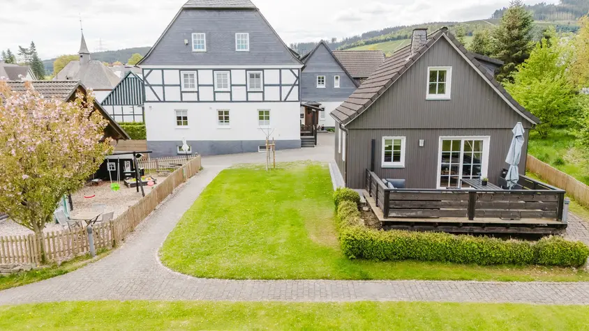 Große Rasenfläche vor dem Ferienhaus mit Terrasse und Spielplatz, von oben